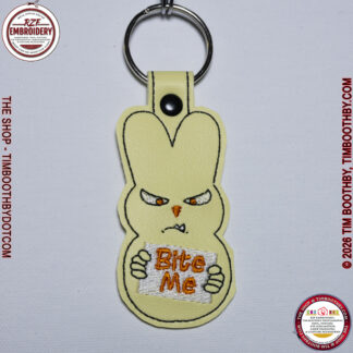 Pastel vinyl key chain of a peep bunny holding a sign that says Bite Me